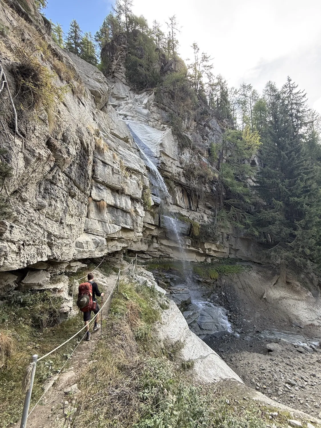 Man walking towards waterfall