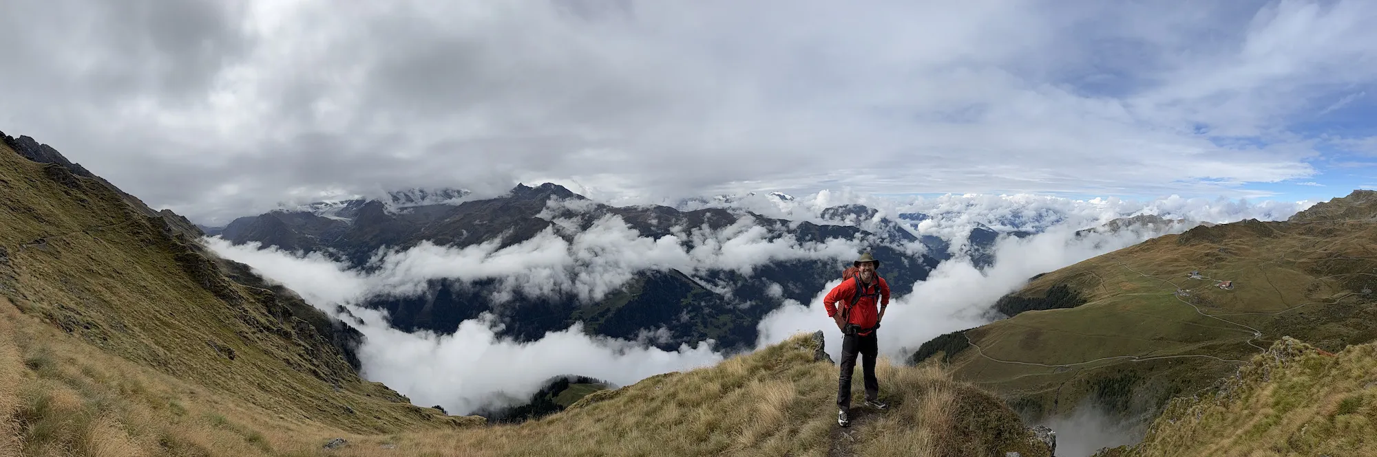 Man on ledge with clouds in the background