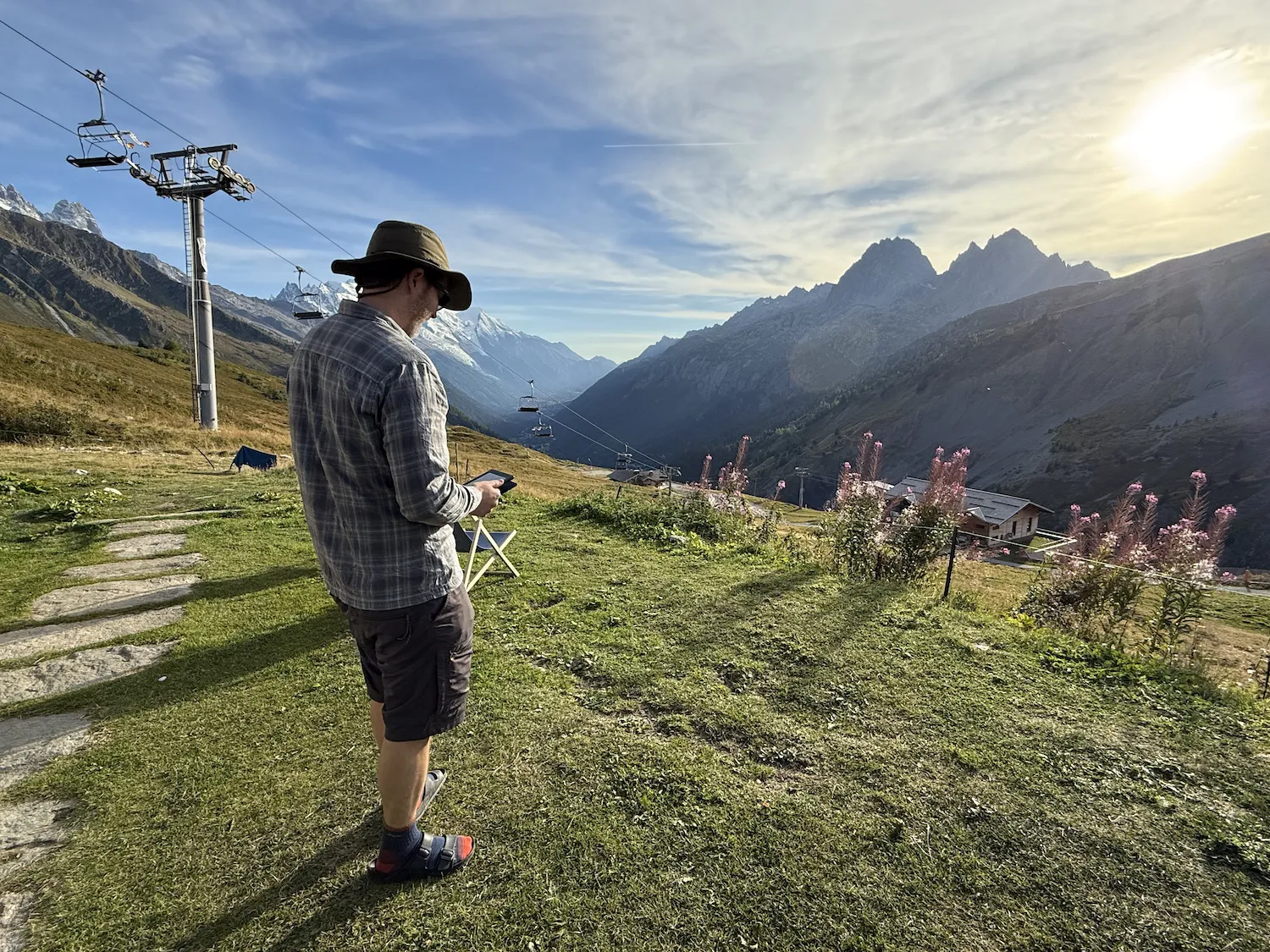 Grant standing reading a kindle with mountains in the background