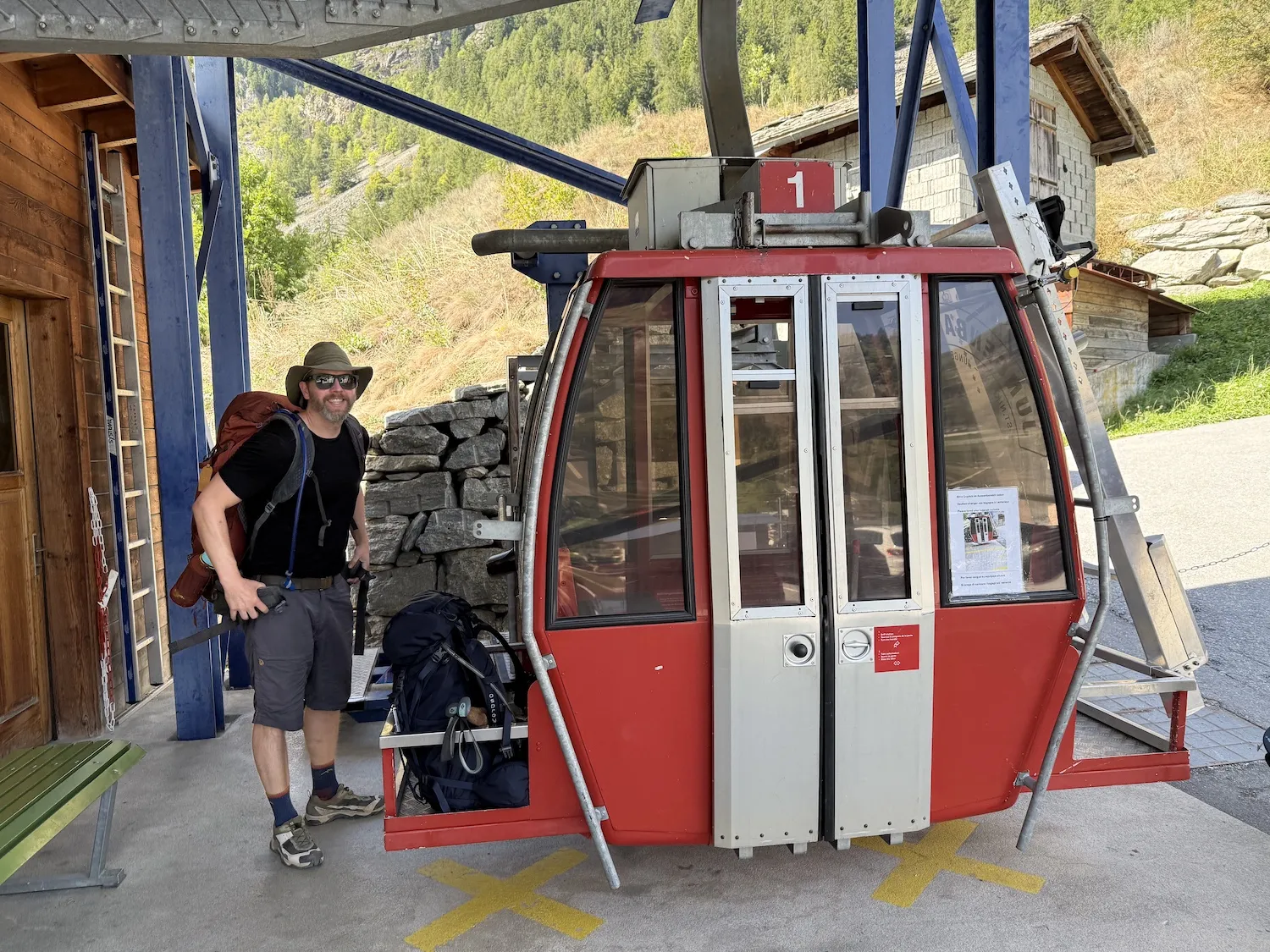 Man next to red gondola holding bags