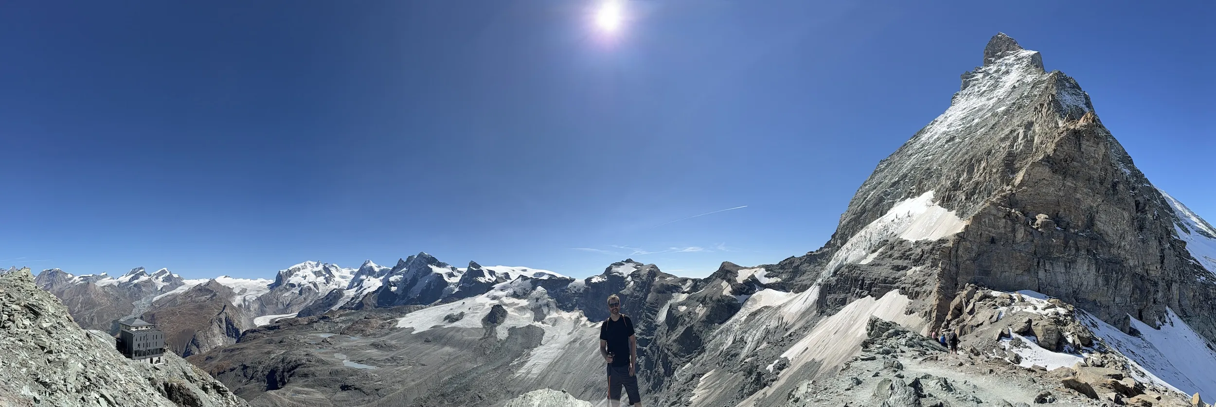 Man in front of the Matterhorn and a hut