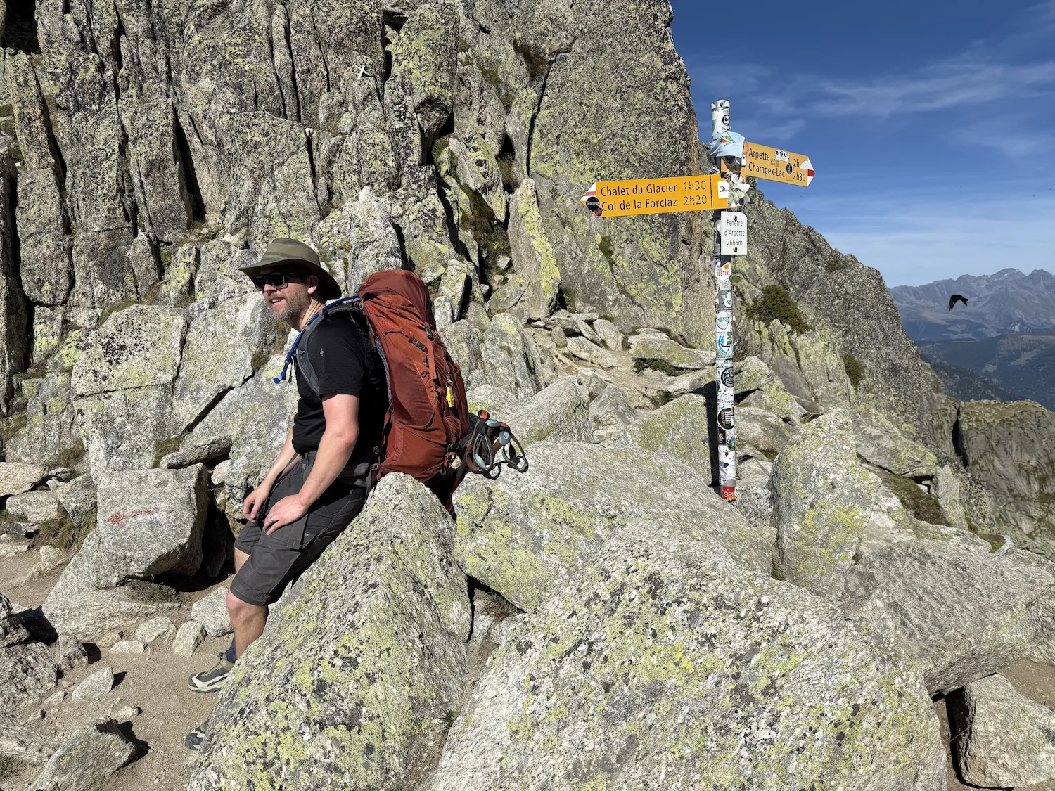 Grant sitting on the summit with a sign
