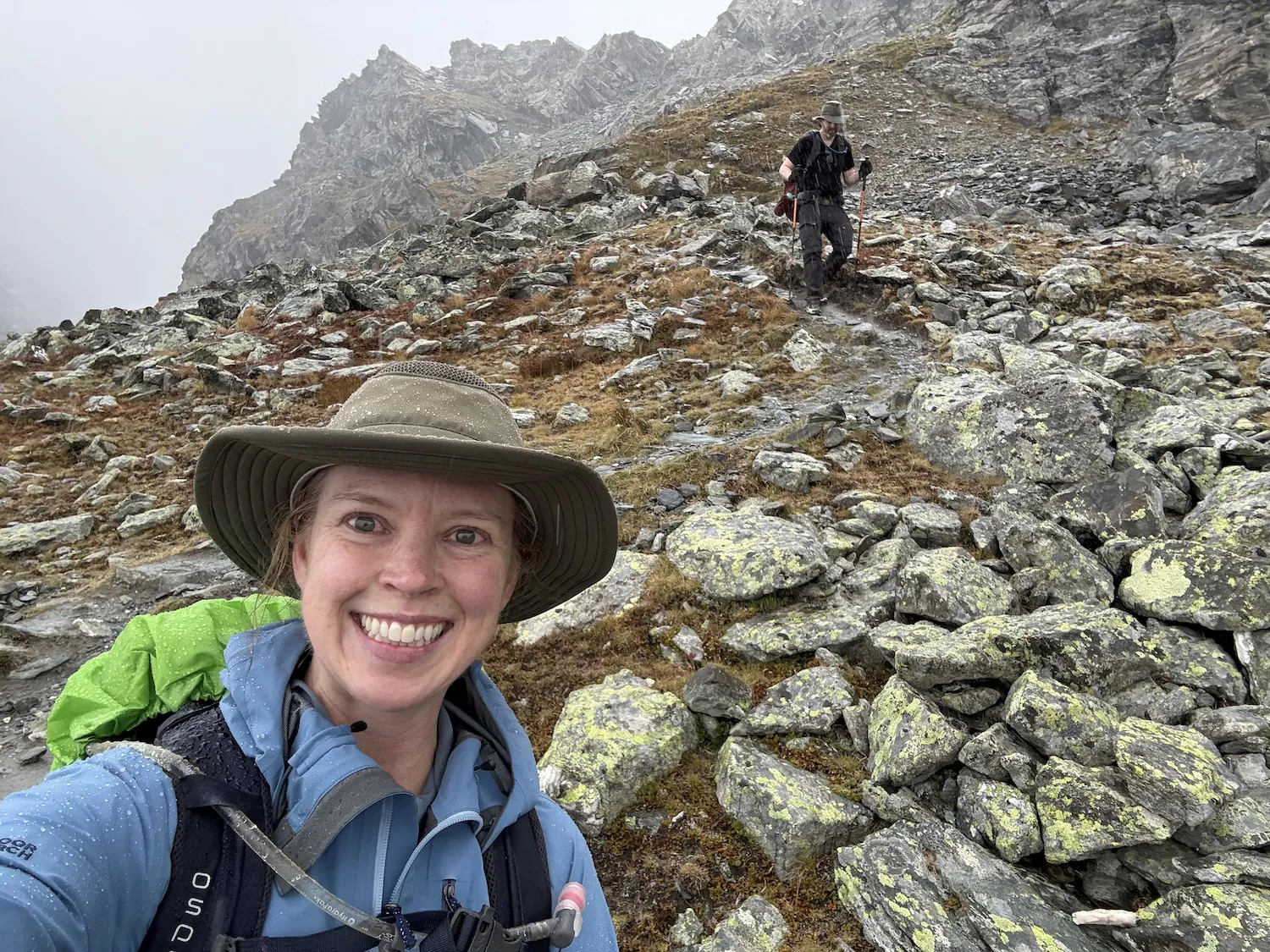 Woman taking selfie with man hiking in the background