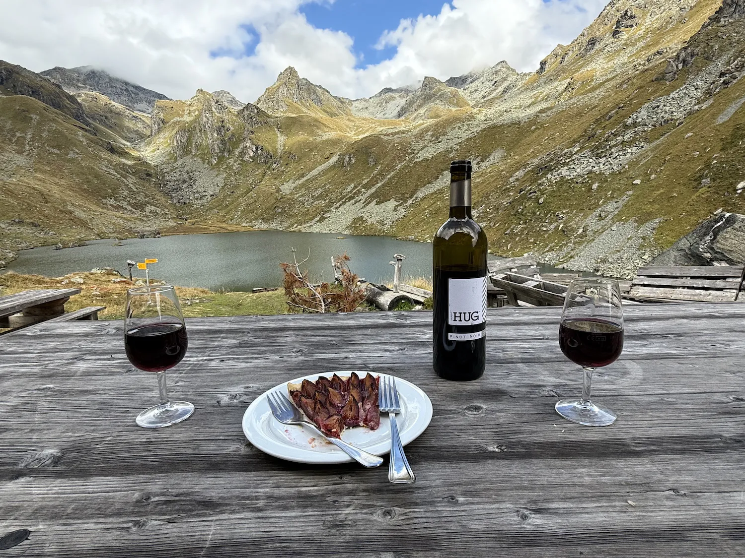 Wine and fruit tart on a table in front of a lake