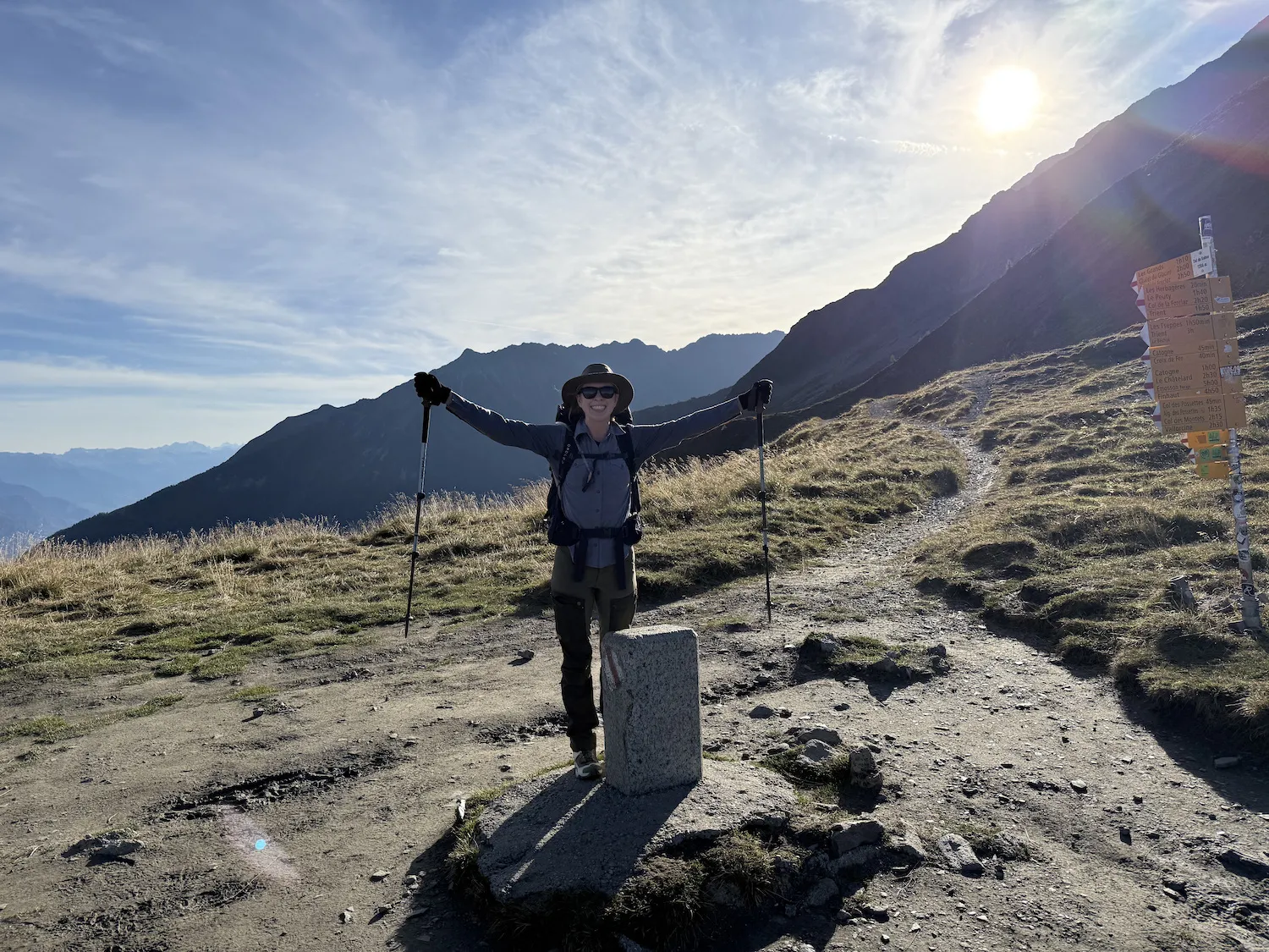 Sheryl standing in front of mountains on a border marker