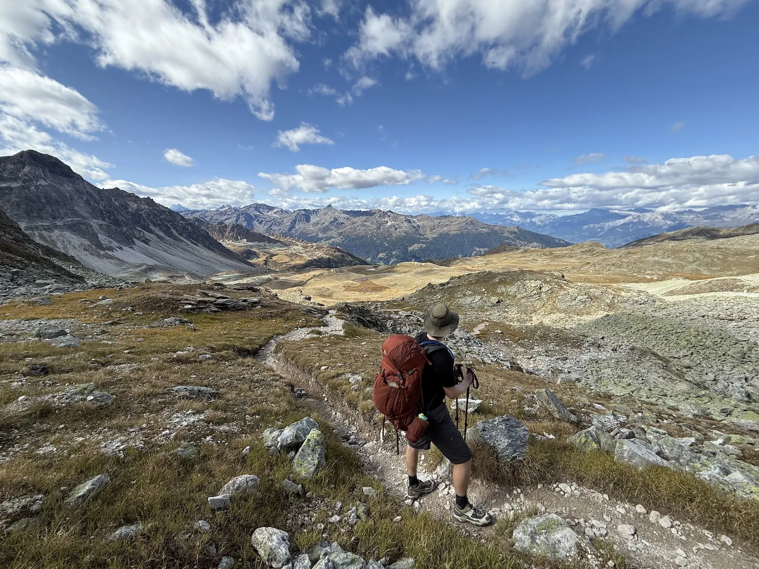 Man with pack looking away towards the clouds and mountains mountains
