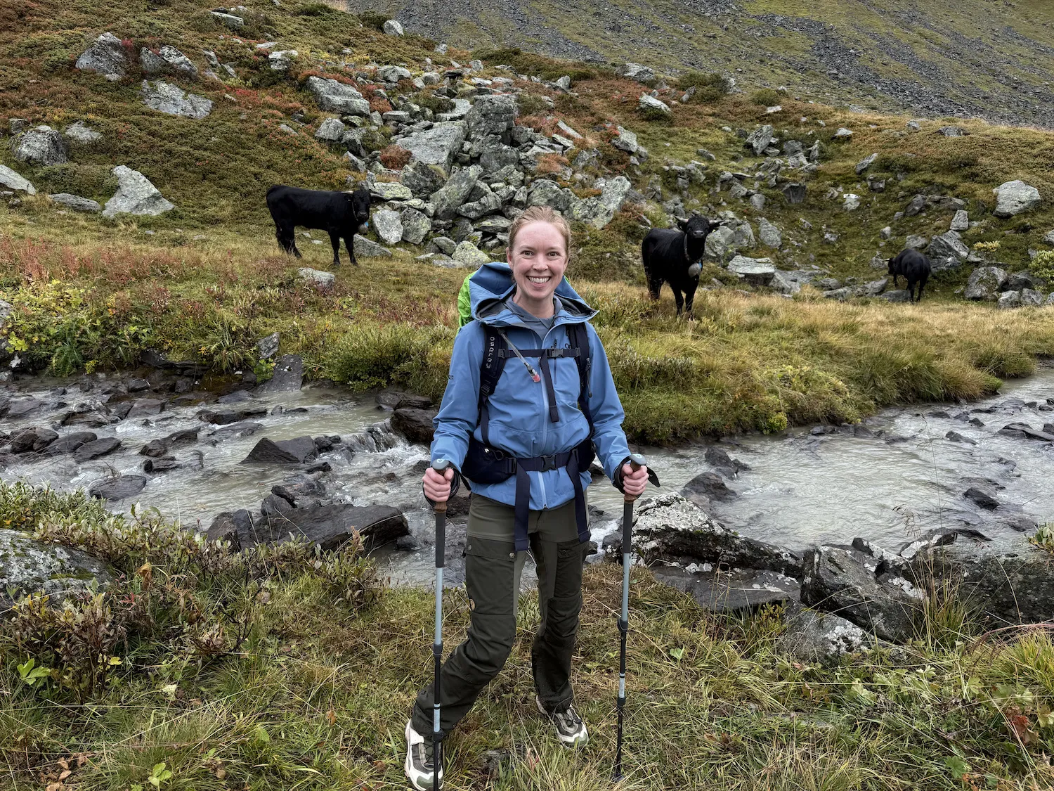 Woman standing in front of two cows near a river