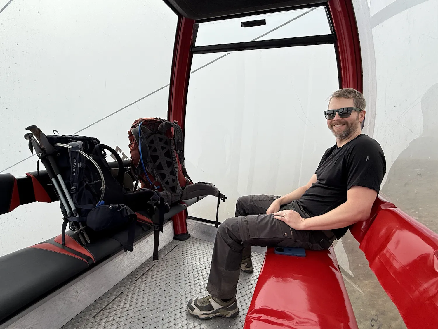 Man next to two backpacks in gondola