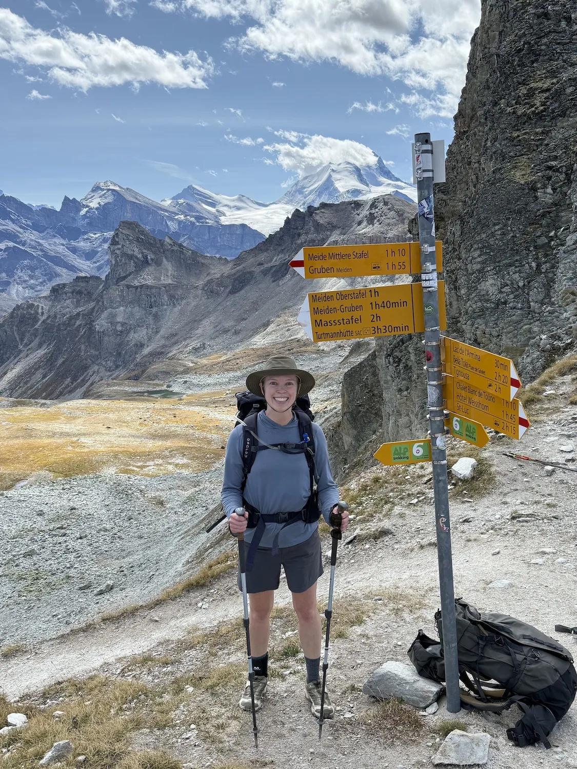 Woman next to summit sign in the mountains