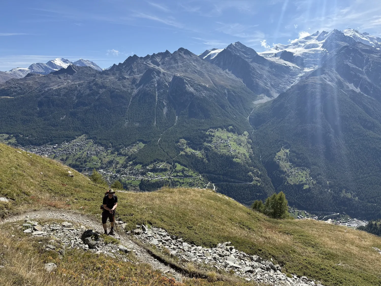 Man posing on path in mountains above small town