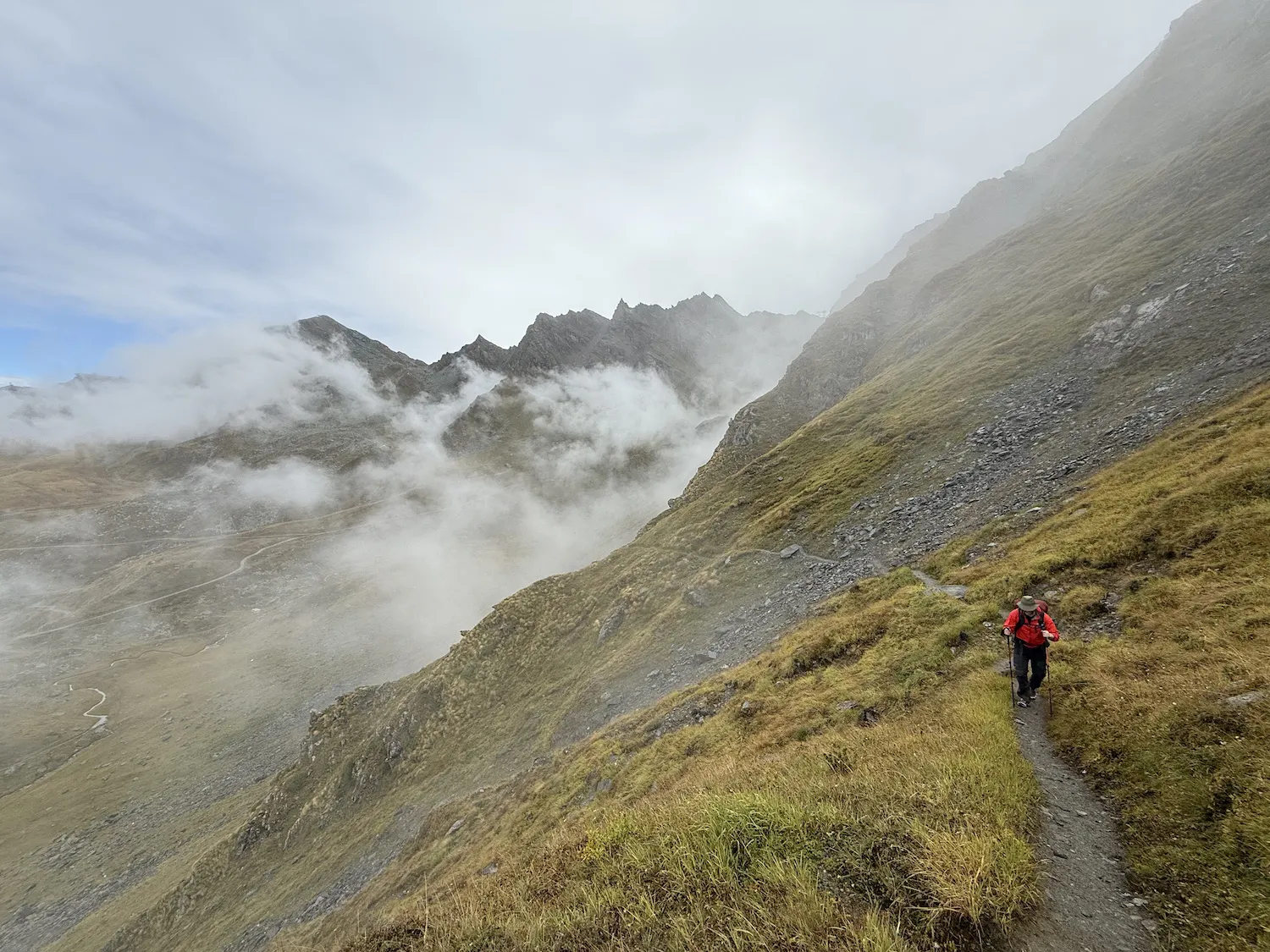 Man climbing along a path with mountains in the background